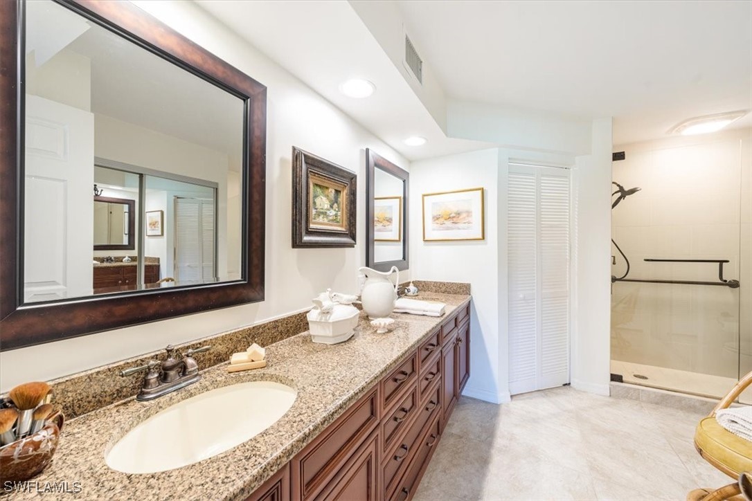 792 Eagle Creek Drive, Unit 101 Naples, FL 34113 - Photo 15 of 16 a bathroom with a granite countertop double vanity sink a mirror and a shower