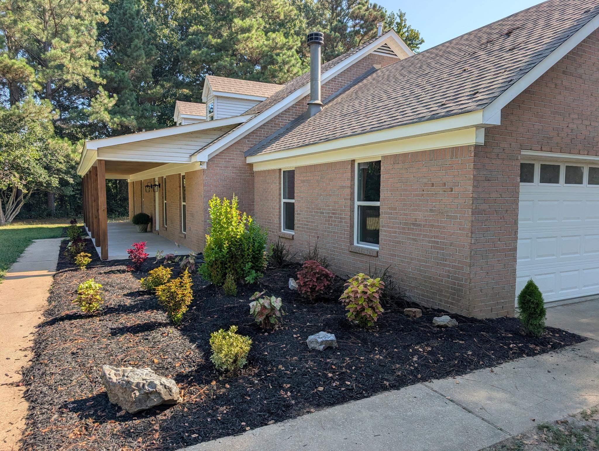 3540 Portersville Road Atoka, TN 38004 - Photo 3 of 37 Brick exterior with a covered porch, white garage door, and a landscaped front bed with mulch