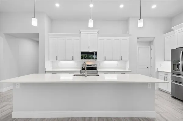 a view of kitchen with kitchen island stainless steel appliances refrigerator stove and wooden floor