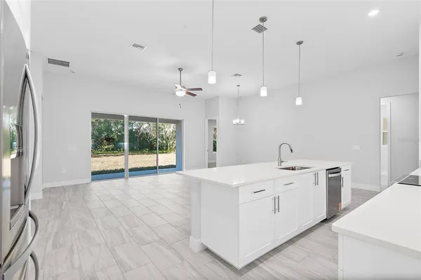 a large white kitchen with a white kitchen island a sink dishwasher and a refrigerator with wooden floor