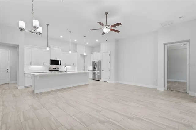 a view of kitchen with kitchen island stainless steel appliances refrigerator stove and wooden floor