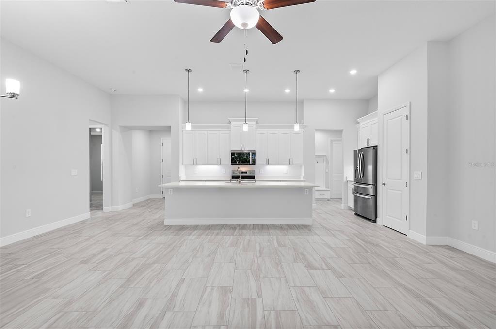 304 North Jungle Road Geneva, FL 32732 - Photo 19 of 49 a large white kitchen with a white kitchen island a sink dishwasher and a refrigerator with wooden floor