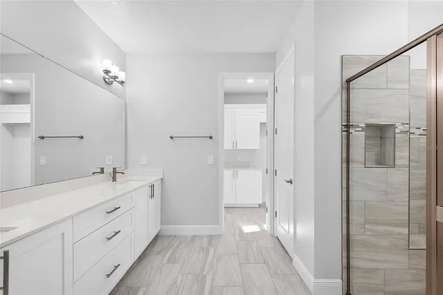 a spacious bathroom with a double vanity sink a large mirror a shower and a bathtub