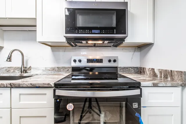 a kitchen with granite countertop white cabinets and a sink