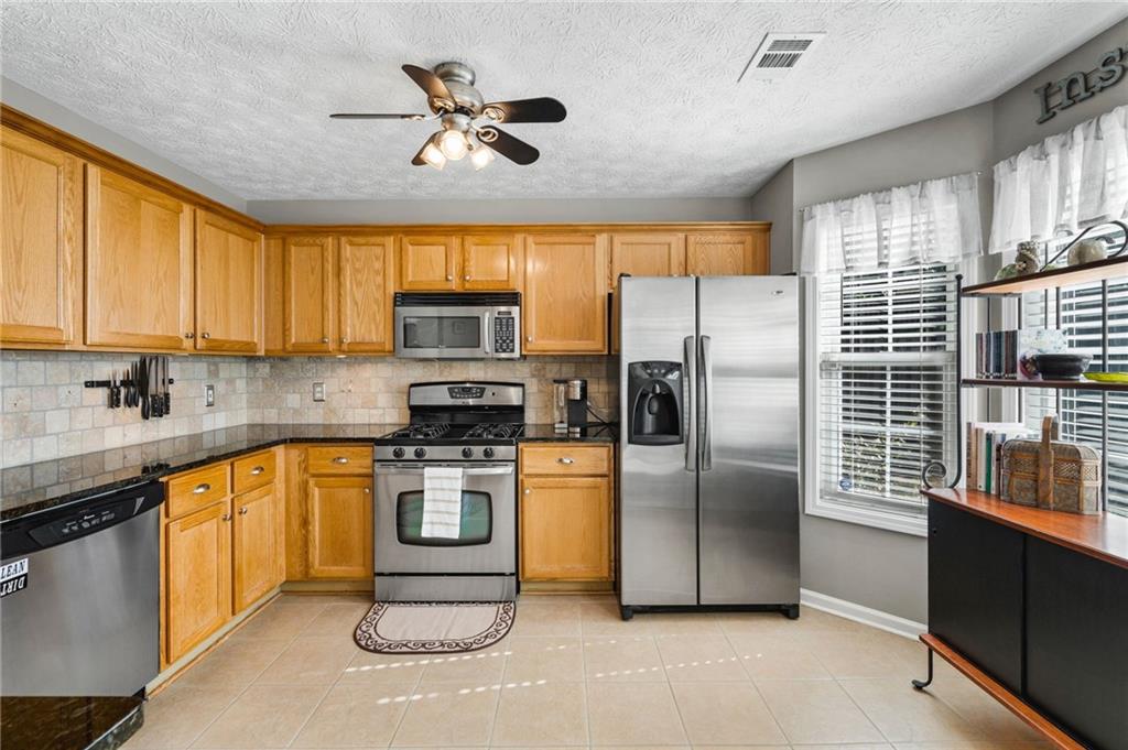 202 Weatherstone Crossing Woodstock, GA 30188 - Photo 11 of 29 a kitchen with stainless steel appliances granite countertop a stove a refrigerator a sink a oven with a dining table and chairs