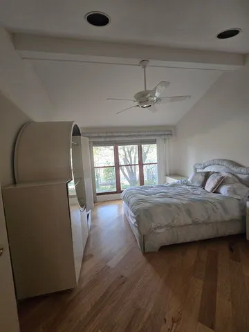 a spacious bedroom with a bed and wooden floor