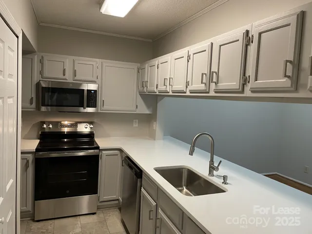a kitchen with white cabinets a sink and stainless steel appliances