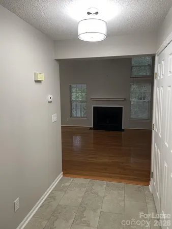 a view of an empty room with wooden floor fireplace and a window