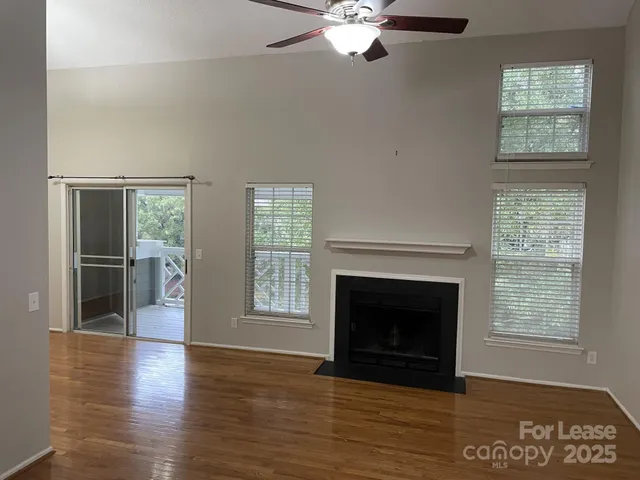 a view of an empty room with wooden floor fireplace and a window