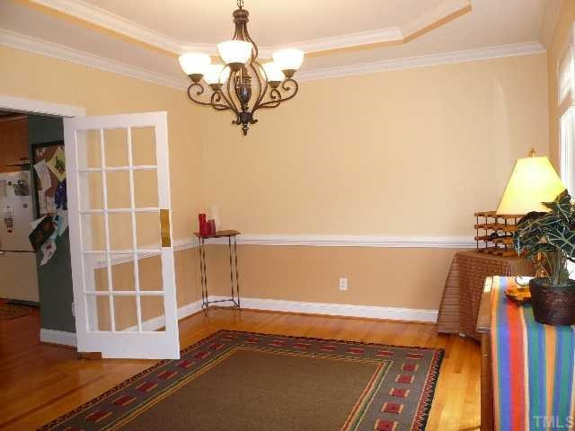 5908 Orchid Valley Road Raleigh, NC 27613 - Photo 5 of 12 The formal dining room features hardwood floors, a trey ceiling, chari rail, crown molding, arched doorway to the foyer and swing glass door to the kitchen. Dining Room