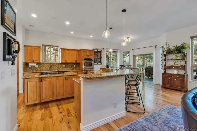 a kitchen with stainless steel appliances granite countertop a stove a refrigerator a sink dishwasher and wooden cabinets with wooden floor