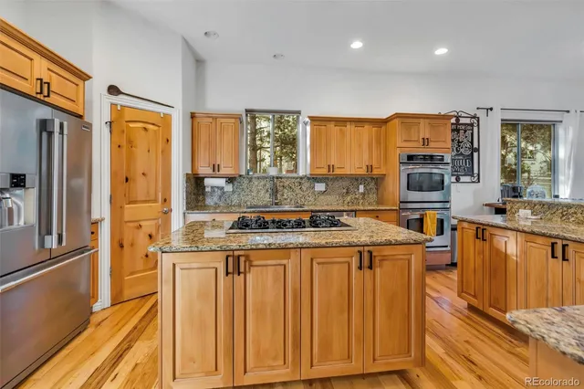 a kitchen with stainless steel appliances kitchen island granite countertop a stove a sink a refrigerator and a microwave