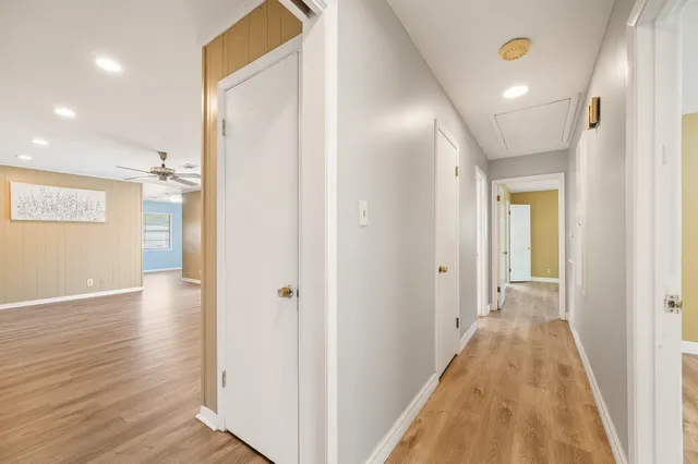 a view of a hallway with wooden floor and a bathroom