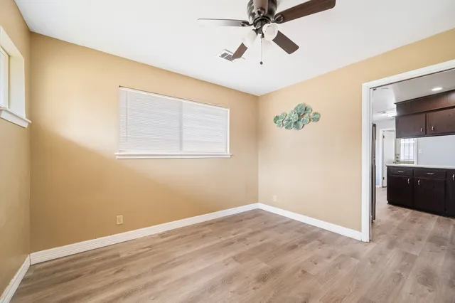 a view of empty room with wooden floor and fan