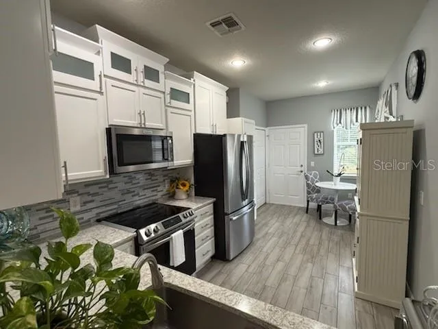 a kitchen with stainless steel appliances granite countertop a refrigerator stove and microwave