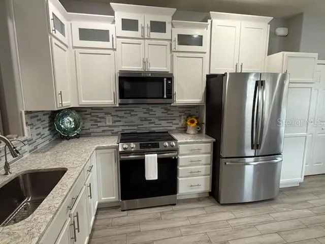 a kitchen with stainless steel appliances granite countertop a refrigerator a stove a sink and a microwave