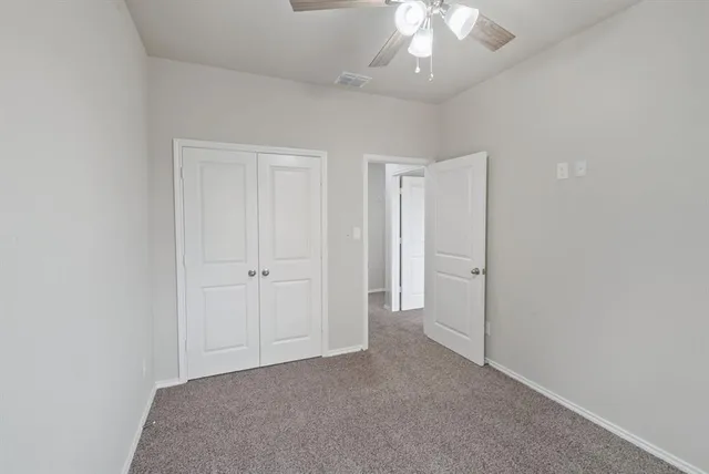 a view of an empty room and chandelier fan