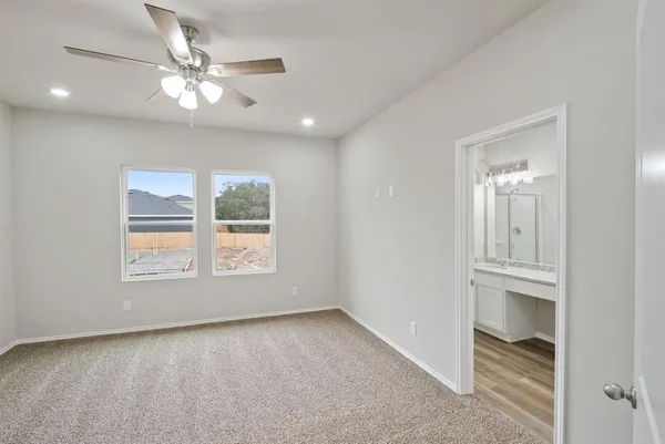 an empty room with chandelier fan and windows