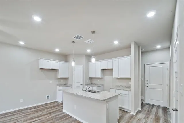 a kitchen with a sink stainless steel appliances white cabinets and wooden floor