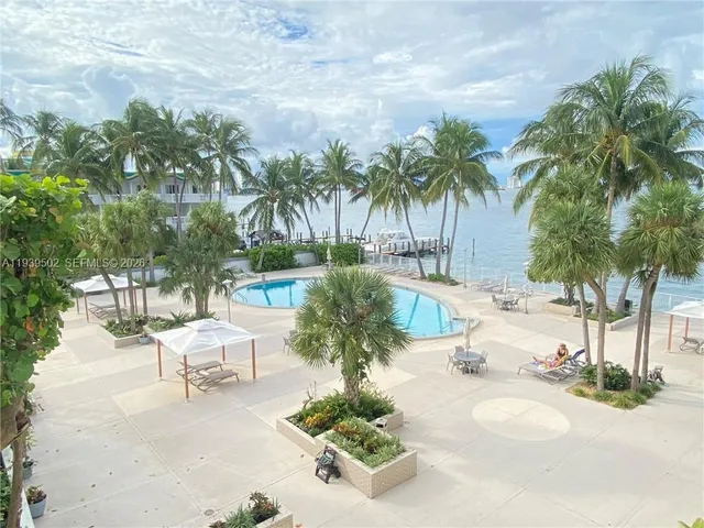 a swimming pool with a lawn chairs under palm trees