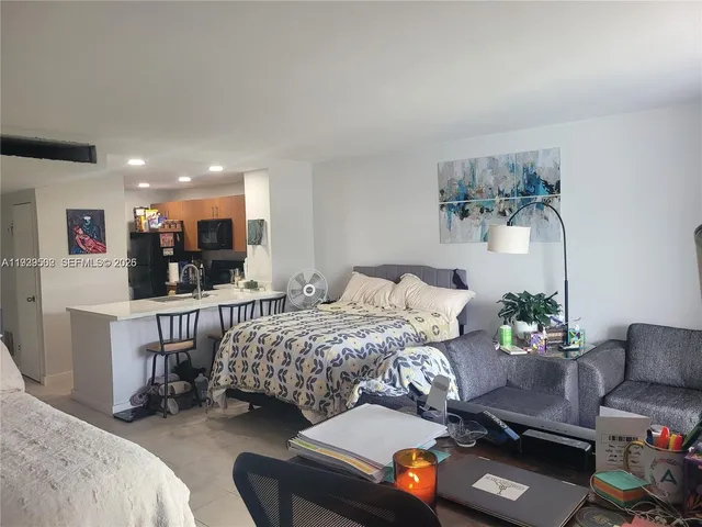 a bedroom with a bed a chair and potted plant on the table