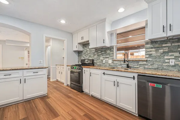 a kitchen with granite countertop cabinets stainless steel appliances a sink and a window