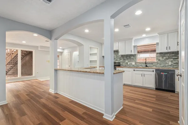 a kitchen with stainless steel appliances granite countertop a refrigerator a sink dishwasher and a stove with wooden floors