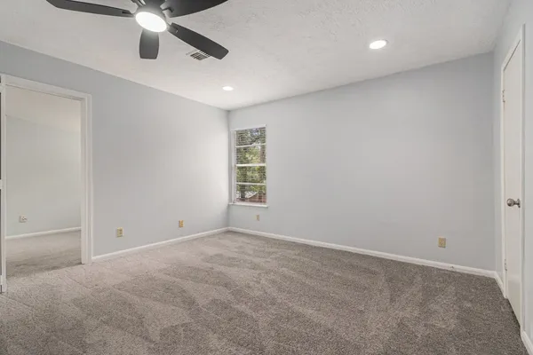 an empty room with windows and fan