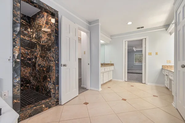 an empty room with chandelier fan and windows