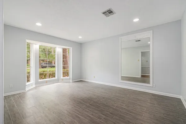 a view of an empty room with wooden floor and a window