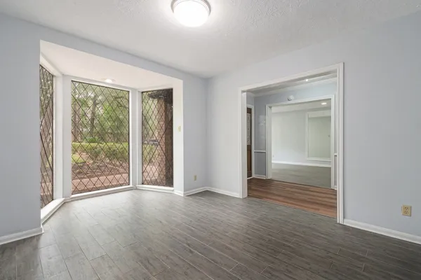a view of an empty room with wooden floor and a window