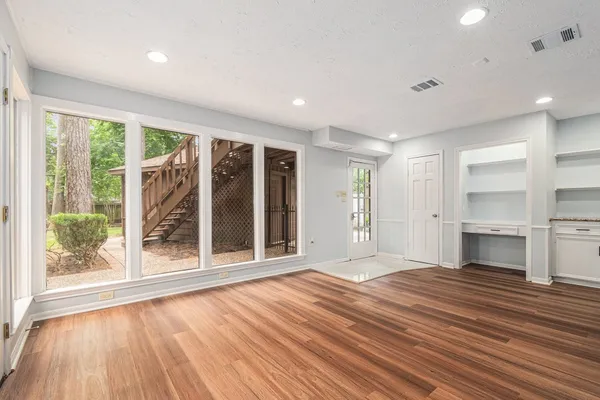a view of an empty room with a window and wooden floor