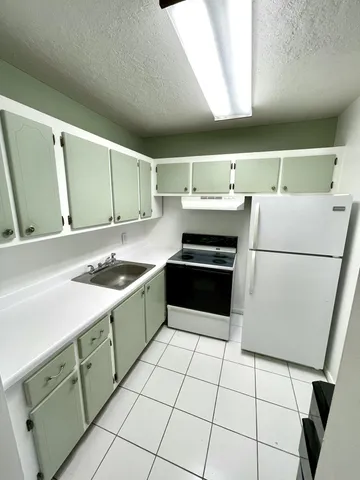 a kitchen with a sink a stove top oven and white cabinets