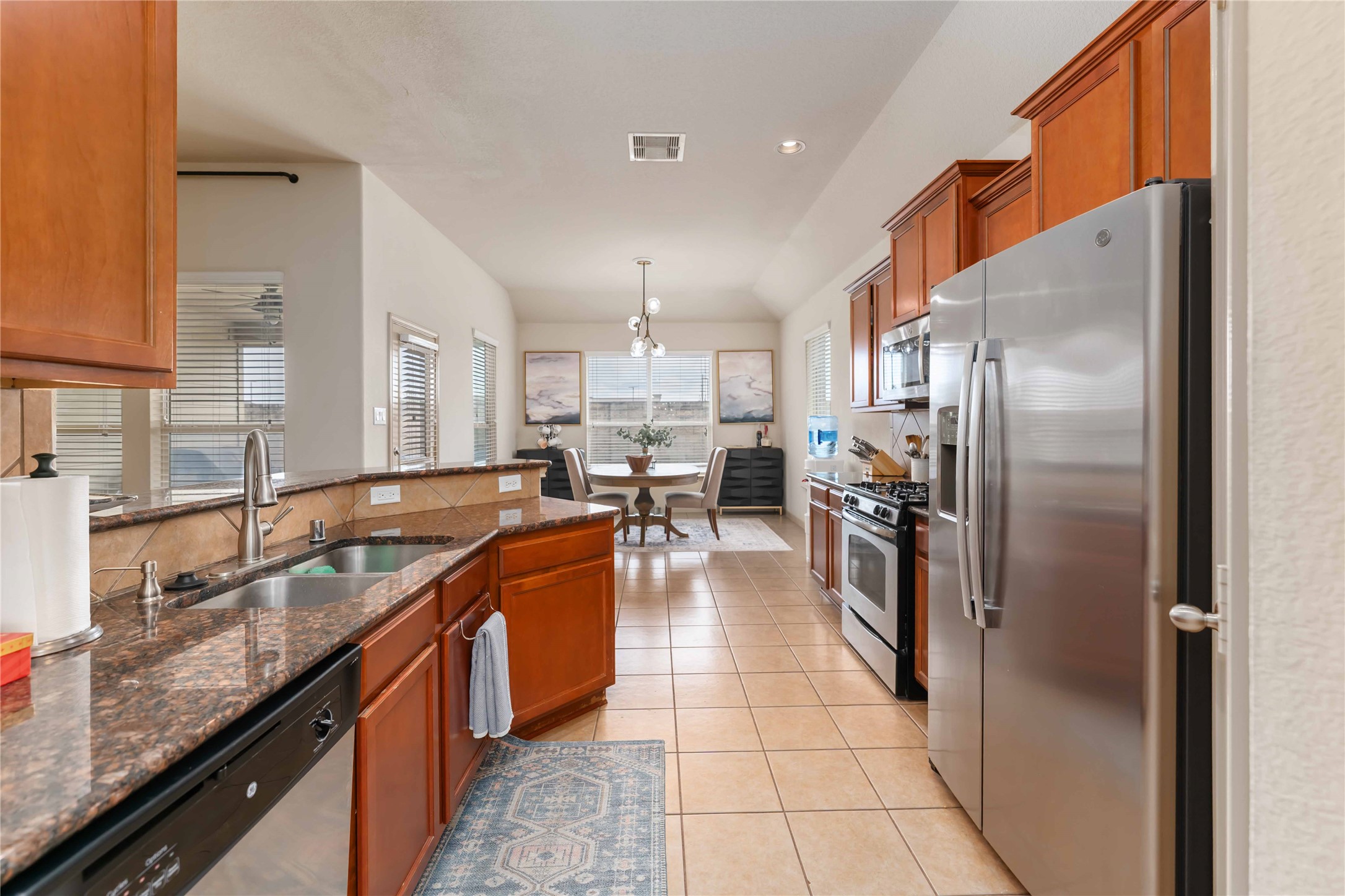2502 Tiger Eye Drive Rosharon, TX 77583 - Photo 21 of 29 This photo showcases a modern kitchen with stainless steel appliances, granite countertops, and wooden cabinets. The open layout leads to a comfortable breakfast area.