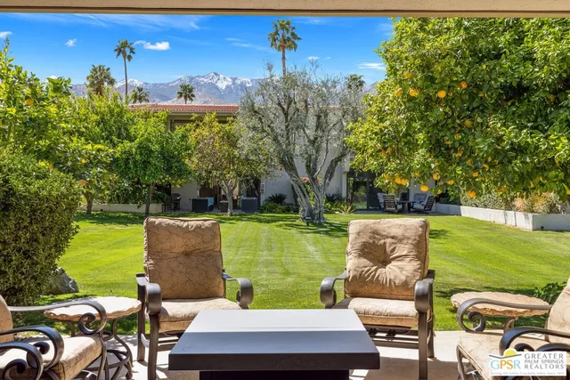 a view of a patio with couches potted plants and a big yard