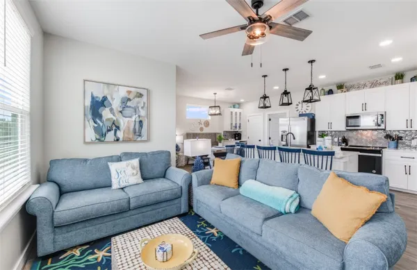 a living room with furniture kitchen view and a large window