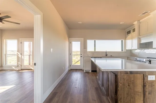 a kitchen with kitchen island granite countertop a sink window and wooden floor