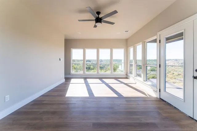 a view of empty room with wooden floor and fan