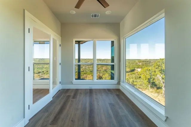 a view of an empty room with wooden floor and a window