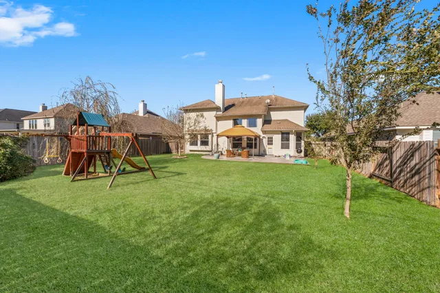 a view of a house with a big yard and large trees