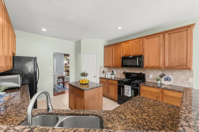 a kitchen with stainless steel appliances granite countertop a sink stove refrigerator and cabinets