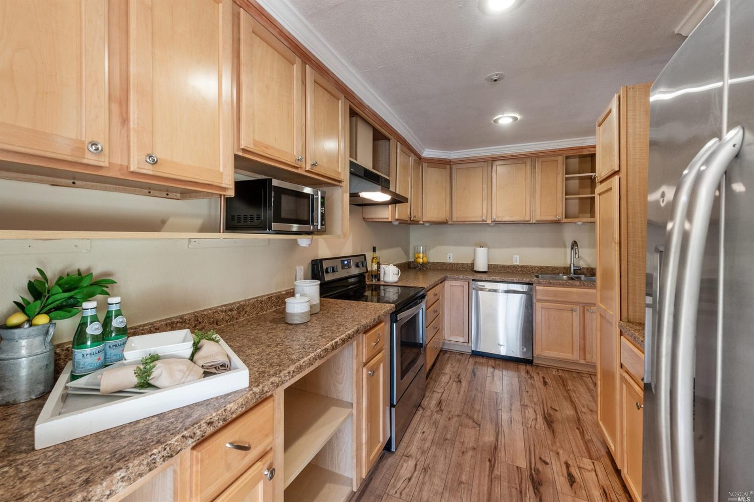 a kitchen with stainless steel appliances granite countertop a sink a stove a refrigerator cabinets and living room view