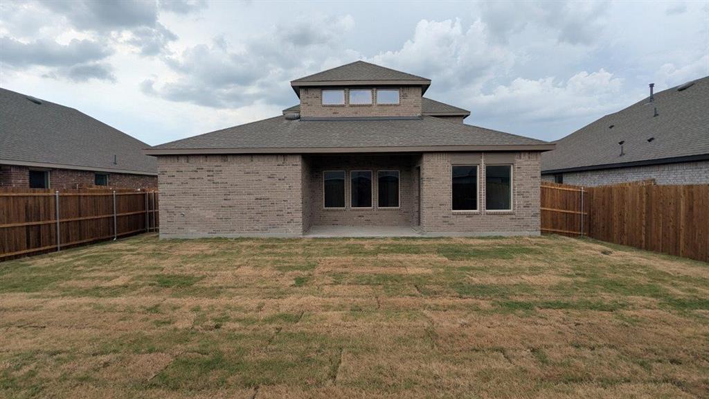 412 Carthage Street Caddo Mills, TX 75135 - Photo 31 of 32 Rear exterior featuring light-colored brick facade and a multi-level roofline with dormer windows