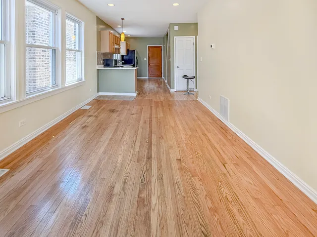 a view of a big room with wooden floor and windows