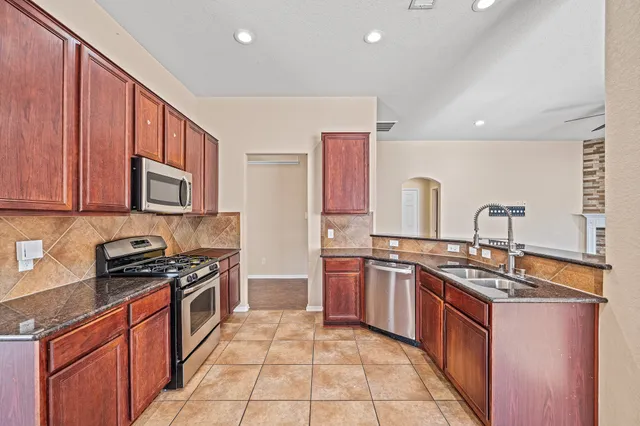 a kitchen with stainless steel appliances granite countertop a stove top oven a sink dishwasher and a microwave oven on the blue kitchen countertops