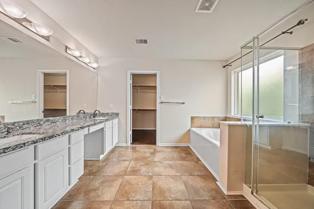 a spacious bathroom with a granite countertop sink a mirror and a bathtub