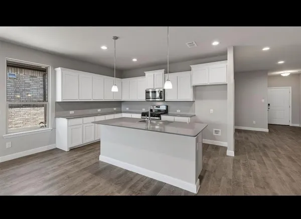 a living room with stainless steel appliances kitchen island granite countertop a sink and cabinets
