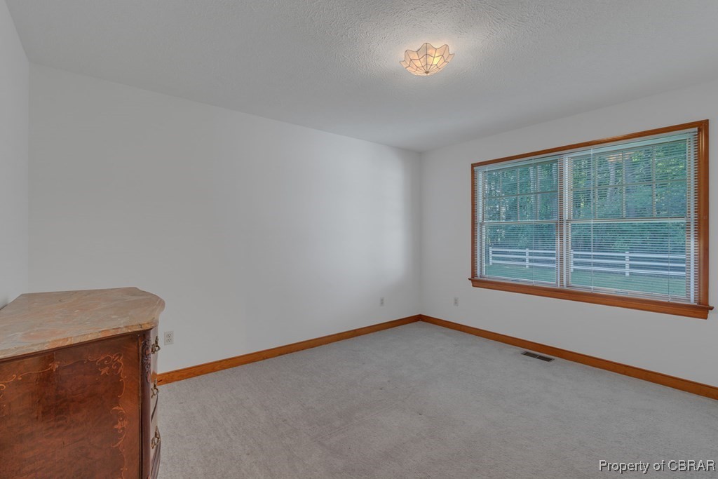 35 Powhatan Road Kilmarnock, VA 22482 - Photo 25 of 42 Spare room featuring baseboards, a textured ceiling, visible vents, and light carpet