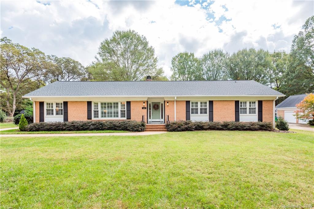 a front view of a house with a garden and trees