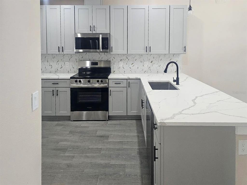 11154 Pendleton Avenue Englewood, FL 34224 - Photo 12 of 32 a kitchen with stainless steel appliances a stove sink and cabinets